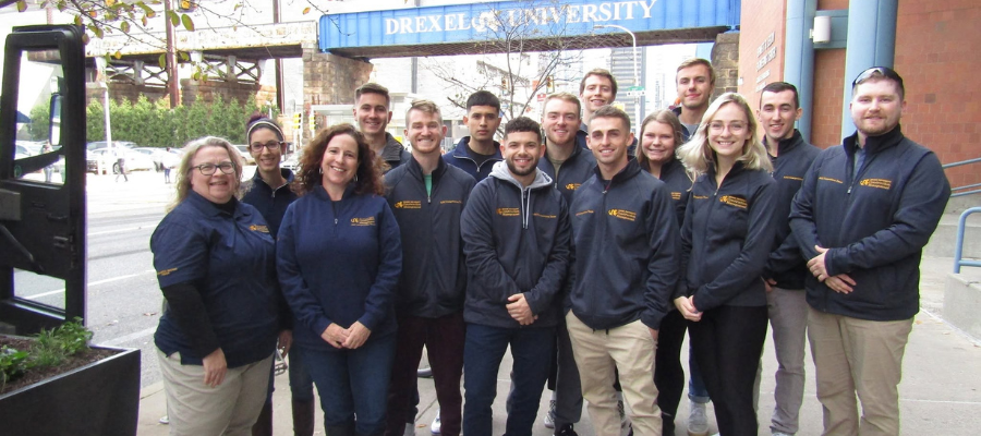 Drexel construction managment students and faculty gather and pose on the street on Drexel campus 